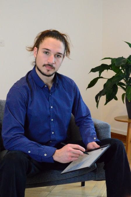 Hassan Hjaij sitzt auf Sessel mit Zeichentablet in der Hand